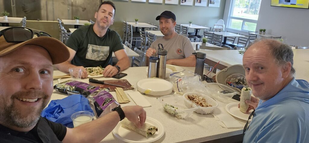 Four guys hanging out in a hotel eating lounge eating dinner