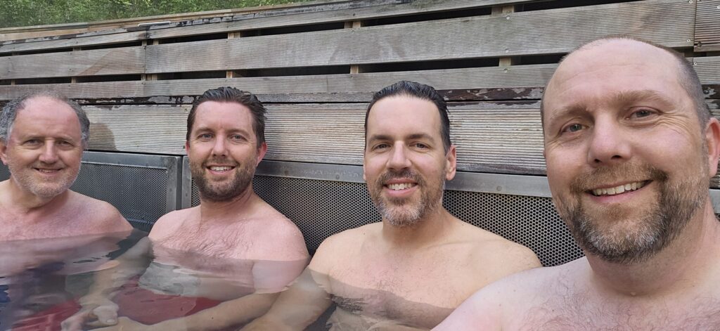 4 men sitting in a natural hot spring