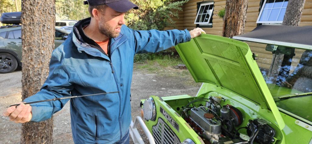 A man checking the oil on a Mini Moke
